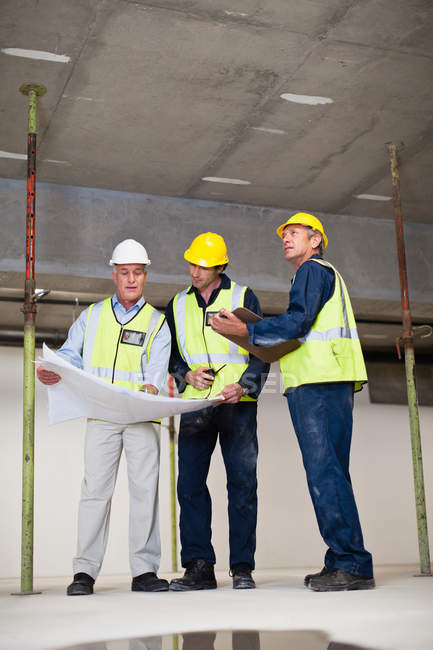 Workers reading blueprints on site — Stock Photo