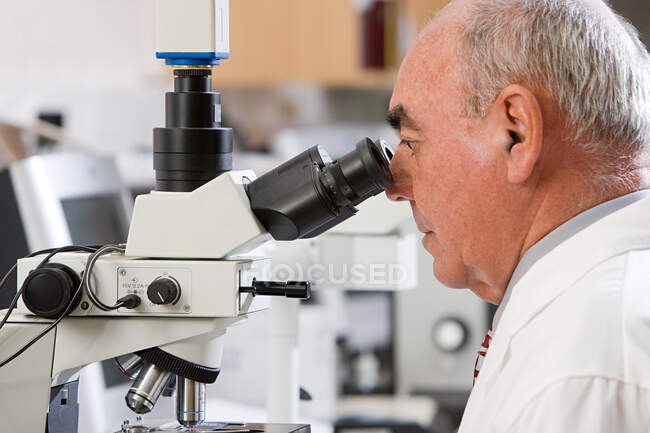 Técnico de laboratorio usando microscopio - foto de stock
