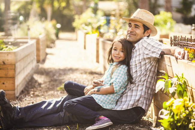 Portrait of girl in community garden sitting on fathers knee — Stock Photo