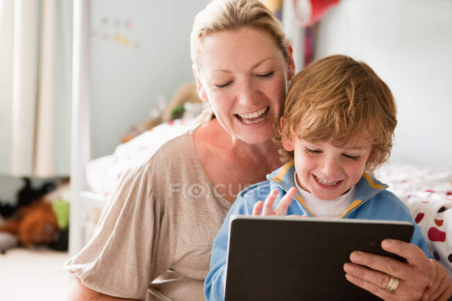 Madre utilizzando un tablet digitale con suo figlio — Foto stock