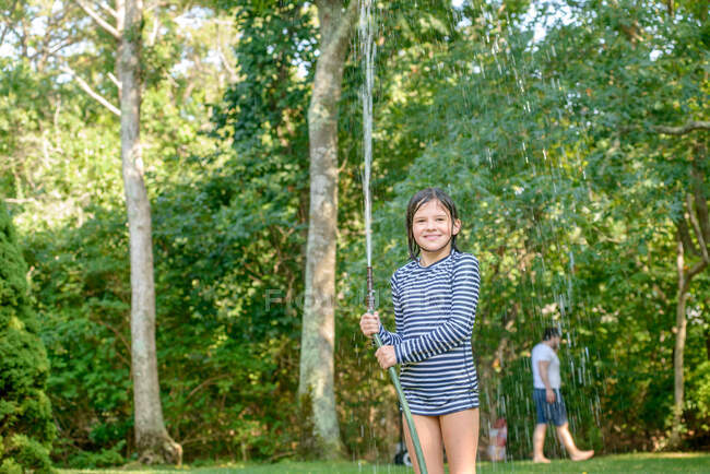 Молода дівчина в саду, тримає садовий шланг — стокове фото