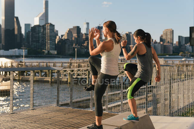 Dos amigos haciendo ejercicio juntos, haciendo levantamientos de piernas al aire libre - foto de stock