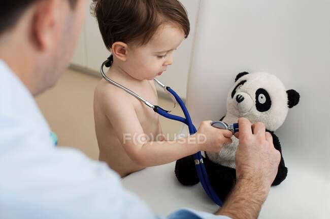 Niño y médico usando estetoscopio en juguete panda - foto de stock