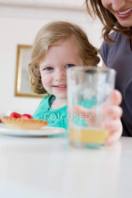 Mädchen hält Glas Saft auf Tisch — Stockfoto