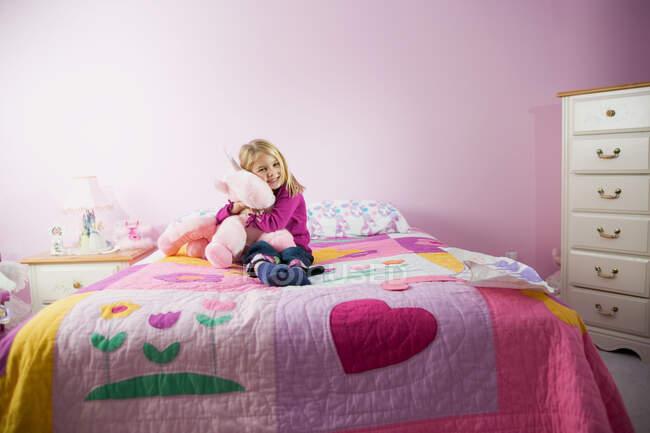 Chica abrazando un juguete en su habitación - foto de stock