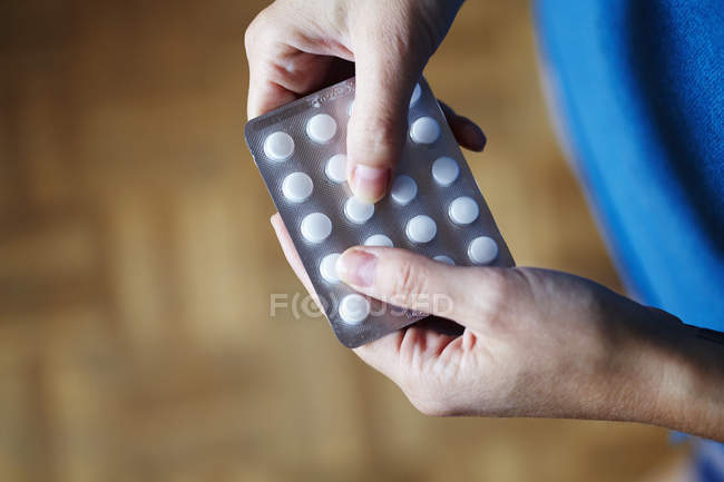 Young woman taking medication from blister pack, close-up partial view — Stock Photo