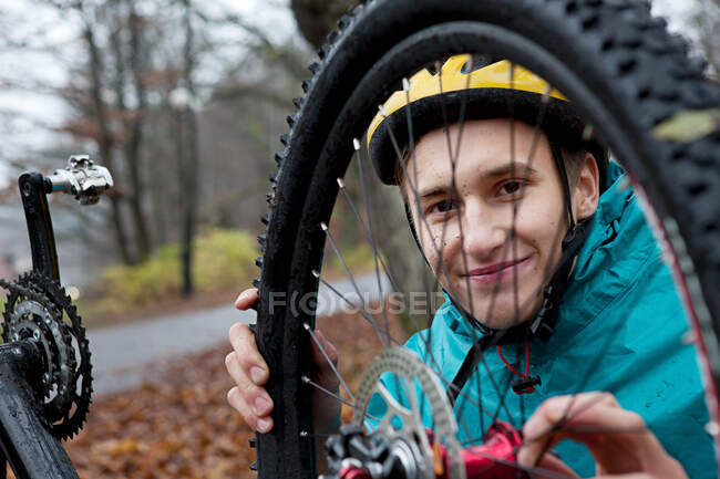 Молодий чоловік фіксує велосипедне колесо в лісі — стокове фото