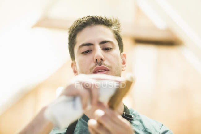 Low angle view of young man crafting wood object, looking down — Stock Photo