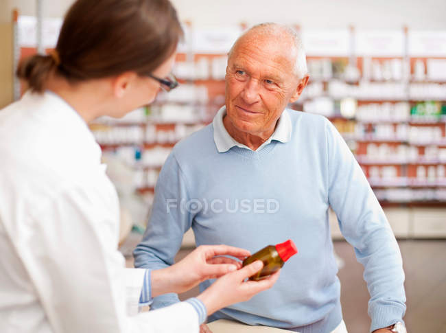 Farmacéutico hablando con el paciente reservado - foto de stock