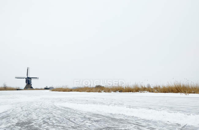 Windmill by frozen lake — Stock Photo