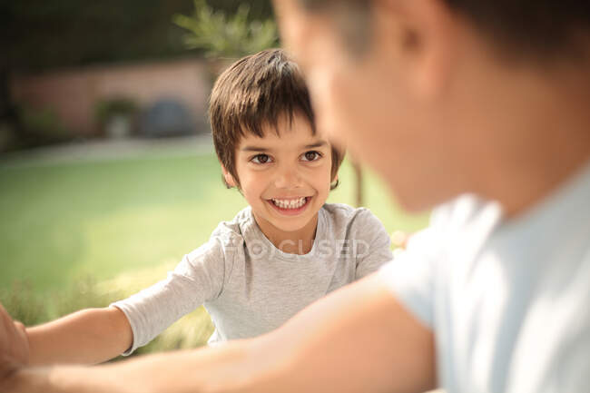 Garoto no jardim sorrindo para o pai, foco diferencial — Fotografia de Stock