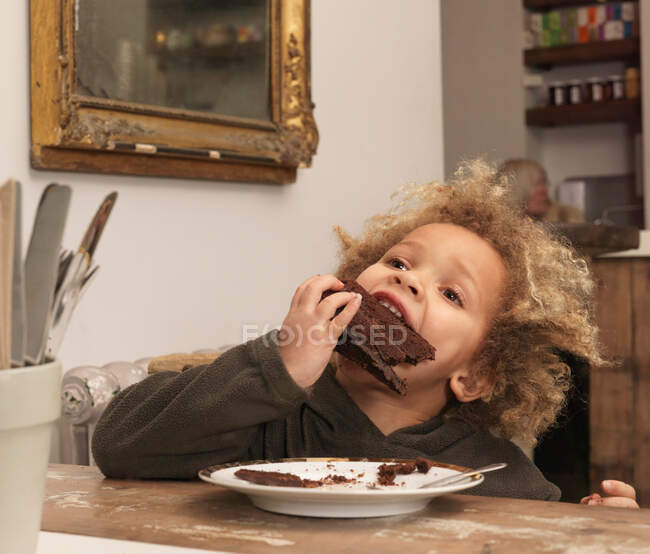 Молодий хлопчик їсть шоколадний торт — стокове фото