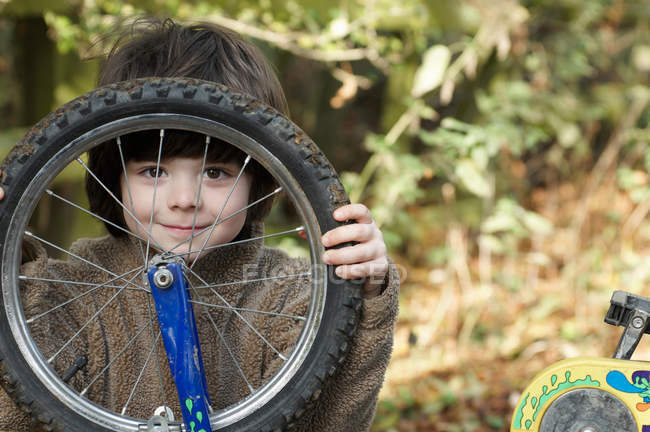 Garçon regardant à travers roue de vélo — Photo de stock