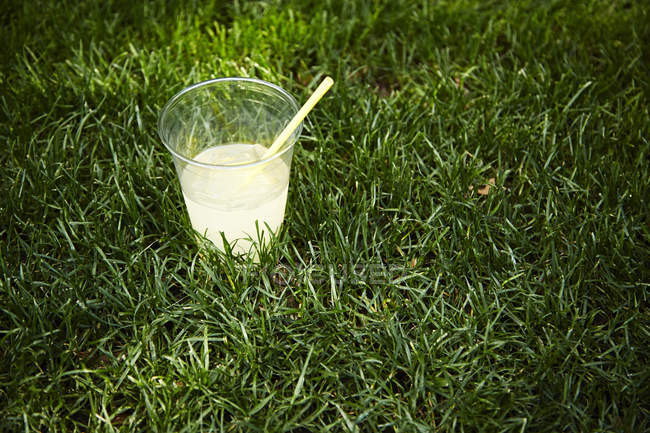 Lemonade in plastic cup on lawn — Stock Photo
