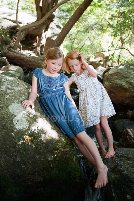 Girls on rock by river — Stock Photo