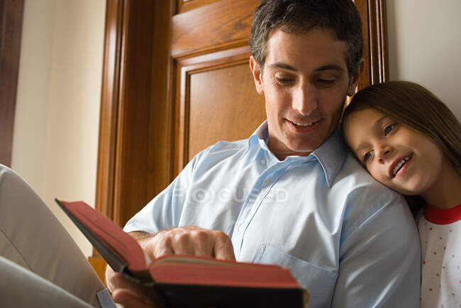 Padre leyendo la Biblia con su hija - foto de stock