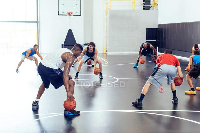 Male trainer and basketball team practicing on court — Stock Photo