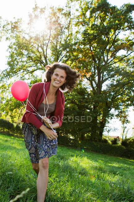 Donna sorridente che trasporta palloncini — Foto stock
