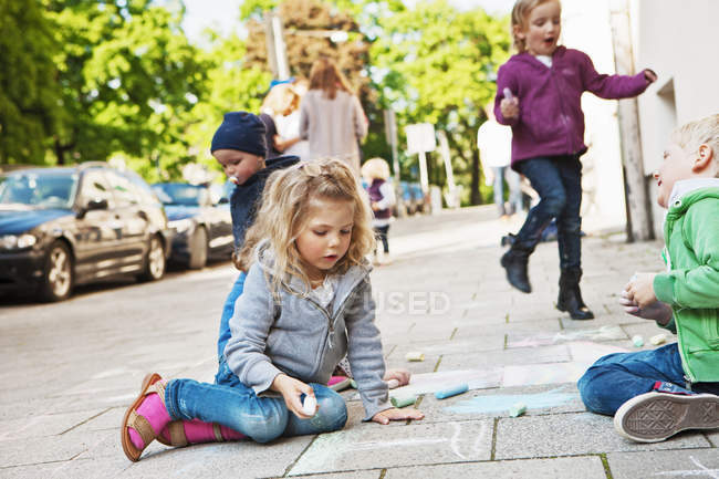 Enfants dessinant sur le trottoir à la craie — Photo de stock