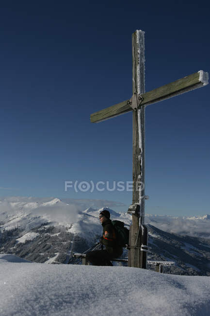 Esquiador encostado à cruz de madeira — Fotografia de Stock