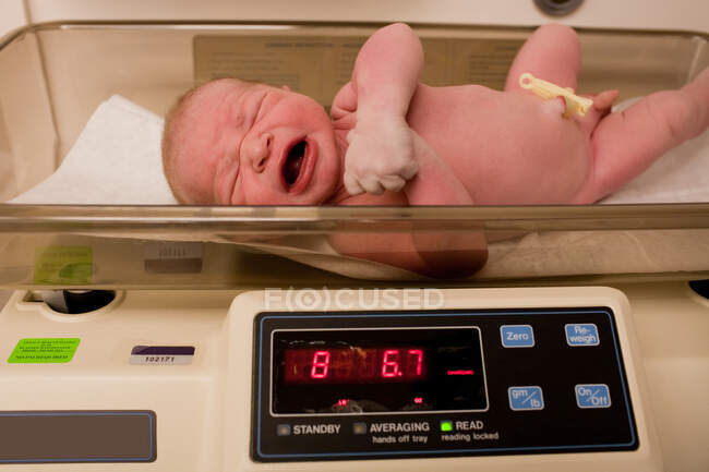 Newborn baby boy on weighing scales — Stock Photo