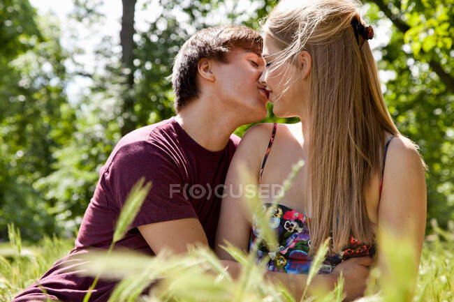 Adolescente pareja besándose en alto hierba - foto de stock
