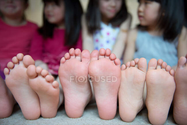 Ragazze sedute insieme a piedi nudi di fila — Foto stock