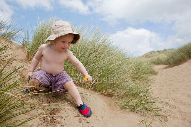 Мальчик играет на песчаной дюне — стоковое фото