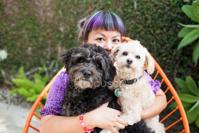 Mitte erwachsene Frau sitzt draußen und umarmt zwei Hunde — Stockfoto