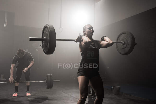 Young woman lifting barbell — Stock Photo