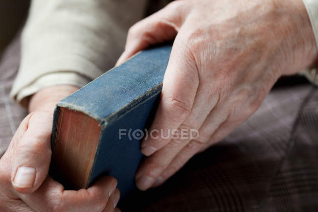 Donna anziana in possesso di libro hardback, primo piano vista parziale — Foto stock