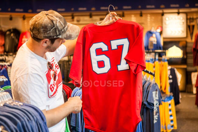 Hombre sosteniendo la camiseta en la tienda - foto de stock