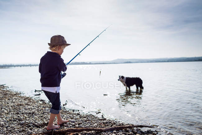 Junge angelt mit Hund in Bach — Stockfoto