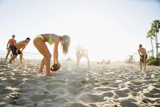 Adult friends playing American football on Newport Beach, California, USA — Stock Photo