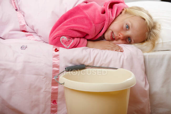 Ill menina na cama com balde — Fotografia de Stock