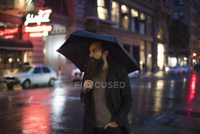 Homme marchant dans la ville la nuit, en utilisant un parapluie, Downtown, San Francisco, California, USA — Photo de stock