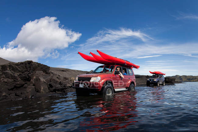 Люди керують автомобілем через мілководне озеро — стокове фото