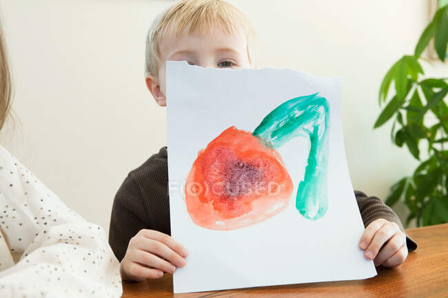 Kleiner Junge hält Gemälde hoch — Stockfoto