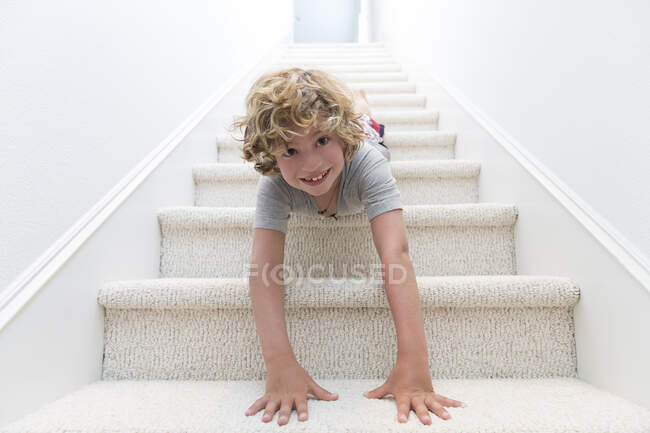 Портрет мальчика, ползающего головой вниз по лестнице — стоковое фото