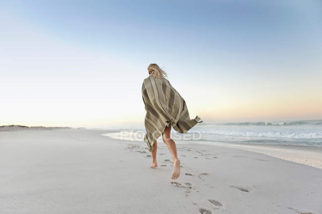 Вид сзади девушки, бегущей по пляжу — стоковое фото