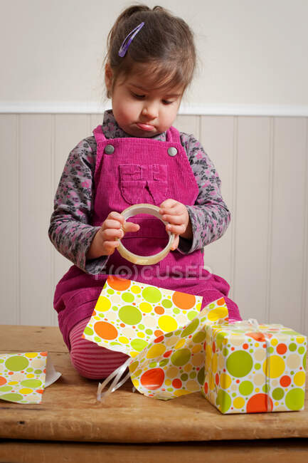 Petite fille fronçant les sourcils comme elle enveloppe un cadeau — Photo de stock