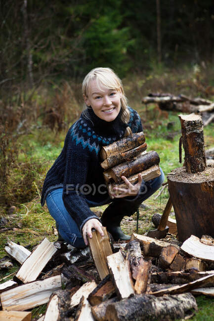 Femme ramassant du bois de chauffage dans la forêt — Photo de stock