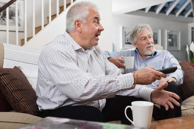 Senior men looking at television in disbelief — Stock Photo