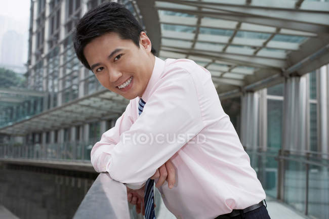Empresário sorridente apoiando-se no corrimão — Fotografia de Stock