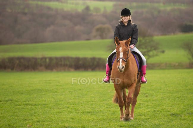 Teenage girl riding horse in field — Stock Photo