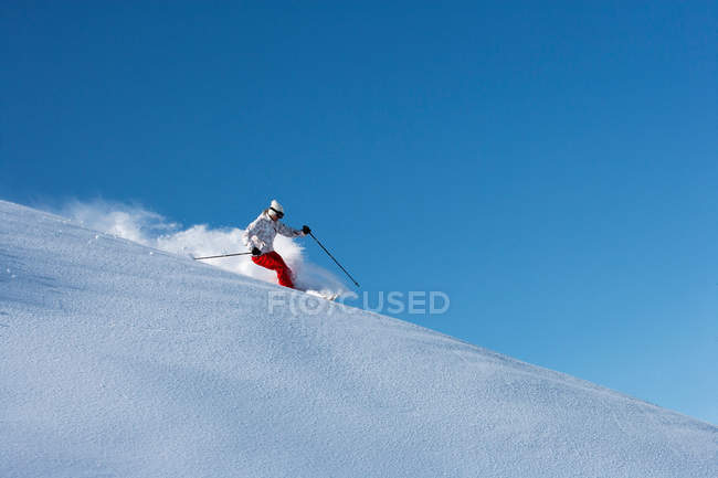 Skieur chevauchant sur une pente enneigée — Photo de stock