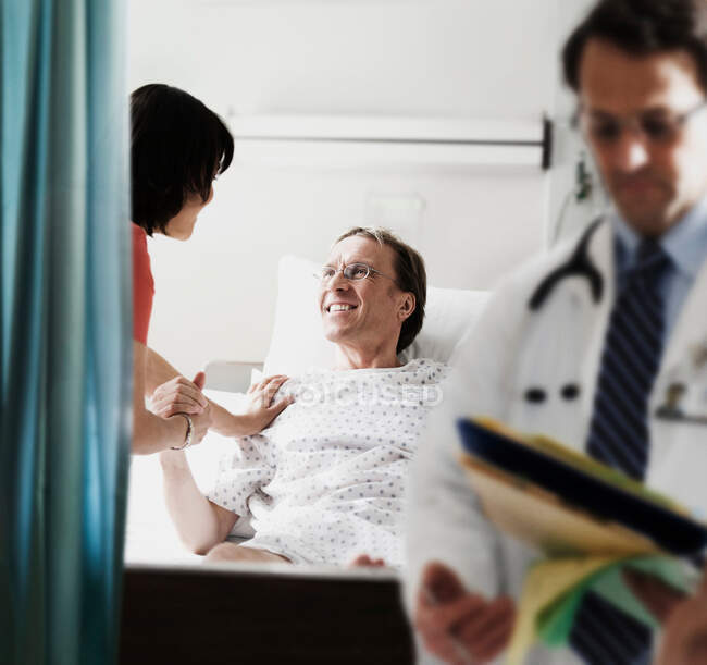 Médico y enfermera revisando al paciente en la cama del hospital - foto de stock
