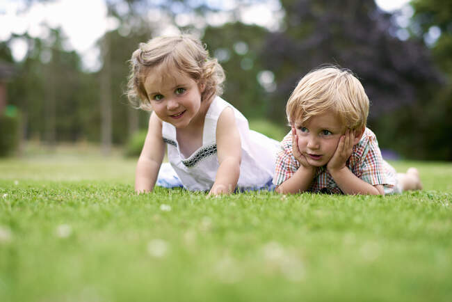 Surface level of boy and girl lying on grass — Stock Photo