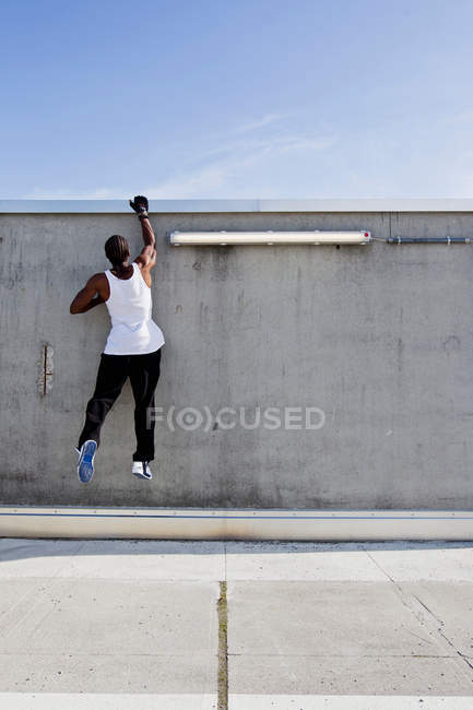 Visão traseira do homem escalar parede na rua da cidade — Fotografia de Stock