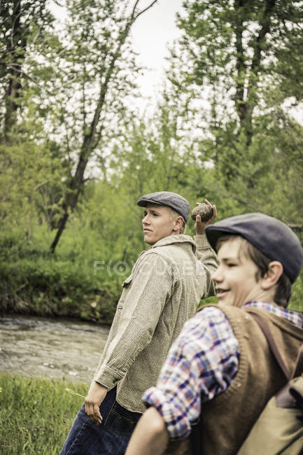 Side view of man and boy wearing flat caps throwing rocks smiling — Stock Photo